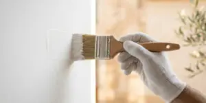 Main d'artisan peintre gantée appliquant de la peinture avec précision, illustration du guide pour choisir son peintre par BL Peinture Rénov