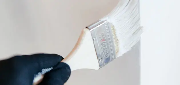Peintre à Sainte-Maxime : pinceau en action sur un mur blanc, intervention BL Peinture Rénov