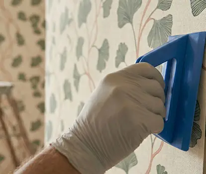 Pose de papier peint à motif végétal par un artisan peintre dans le Var