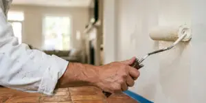 Peintre professionnel appliquant au rouleau une peinture blanche sur un mur intérieur lors de travaux de peinture dans le Var